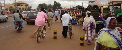 Establishing shot of a bustling city in Ghana. Projects Abroad volunteers doing the HIV/Aids project wander around a market in Ghana.